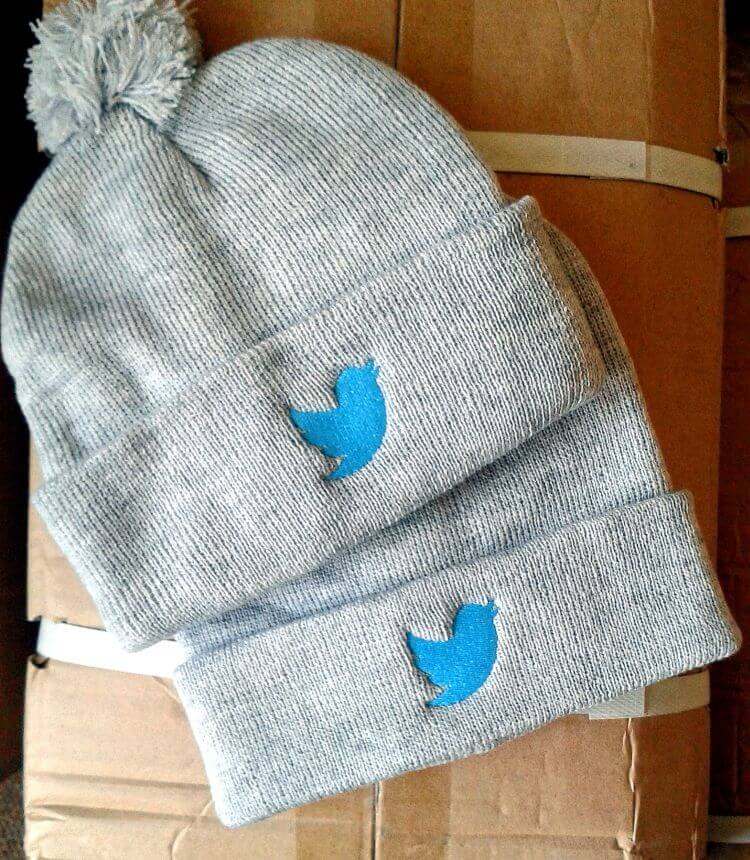 Grey pom-pom beanies with blue bird embroidery on the fold
Pom-pom beanies